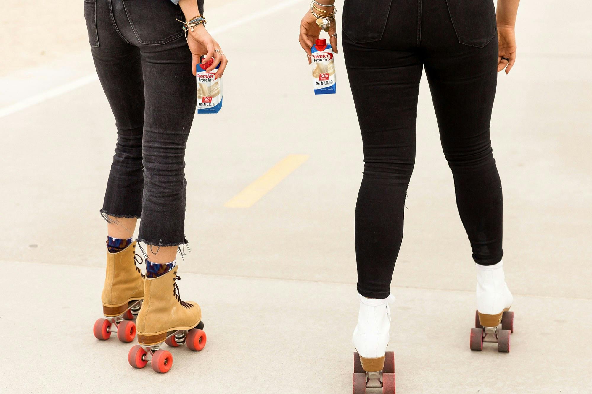 Two people roller skating with Vanilla Premier Protein shakes.